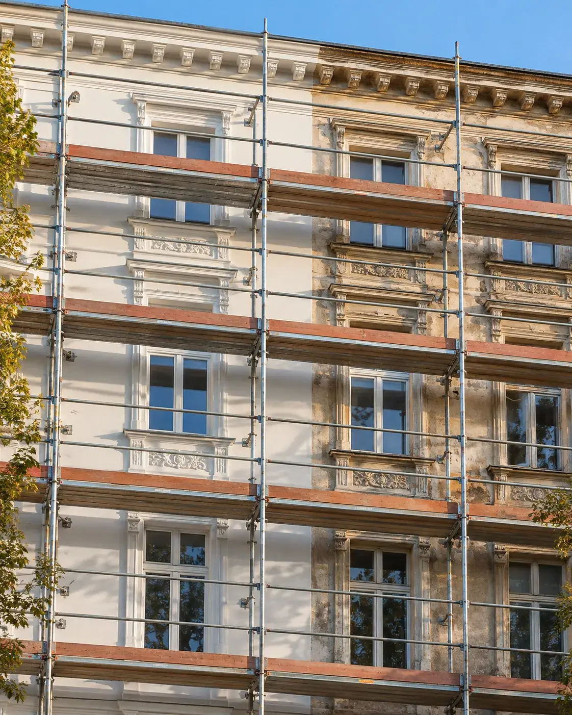 Symbolbild: Altbaufassade mit Fassadengerüst, links frisch gestrichen, rechts noch alter Putz