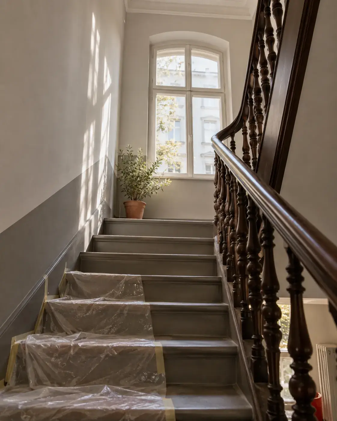 Symbolbild: frisch gestrichenes Treppenhaus mit Holzgeländer und abgedeckten Stufen